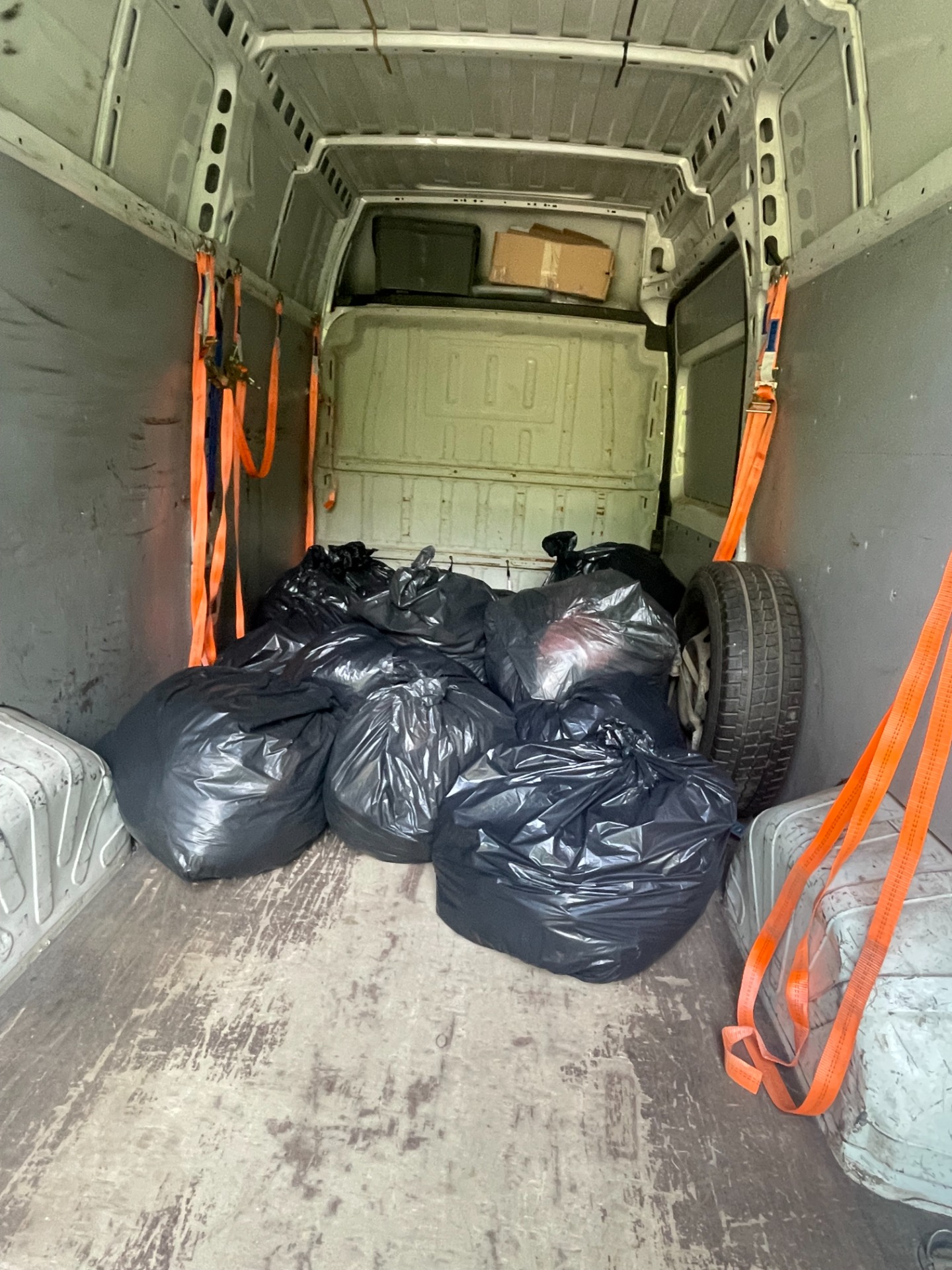 Wywóz i utylizacja worków z ubraniami - usługa transportowa Mrówka Trans. Pojazd dostawczy z załadunkiem odpadów i odzieży do utylizacji.